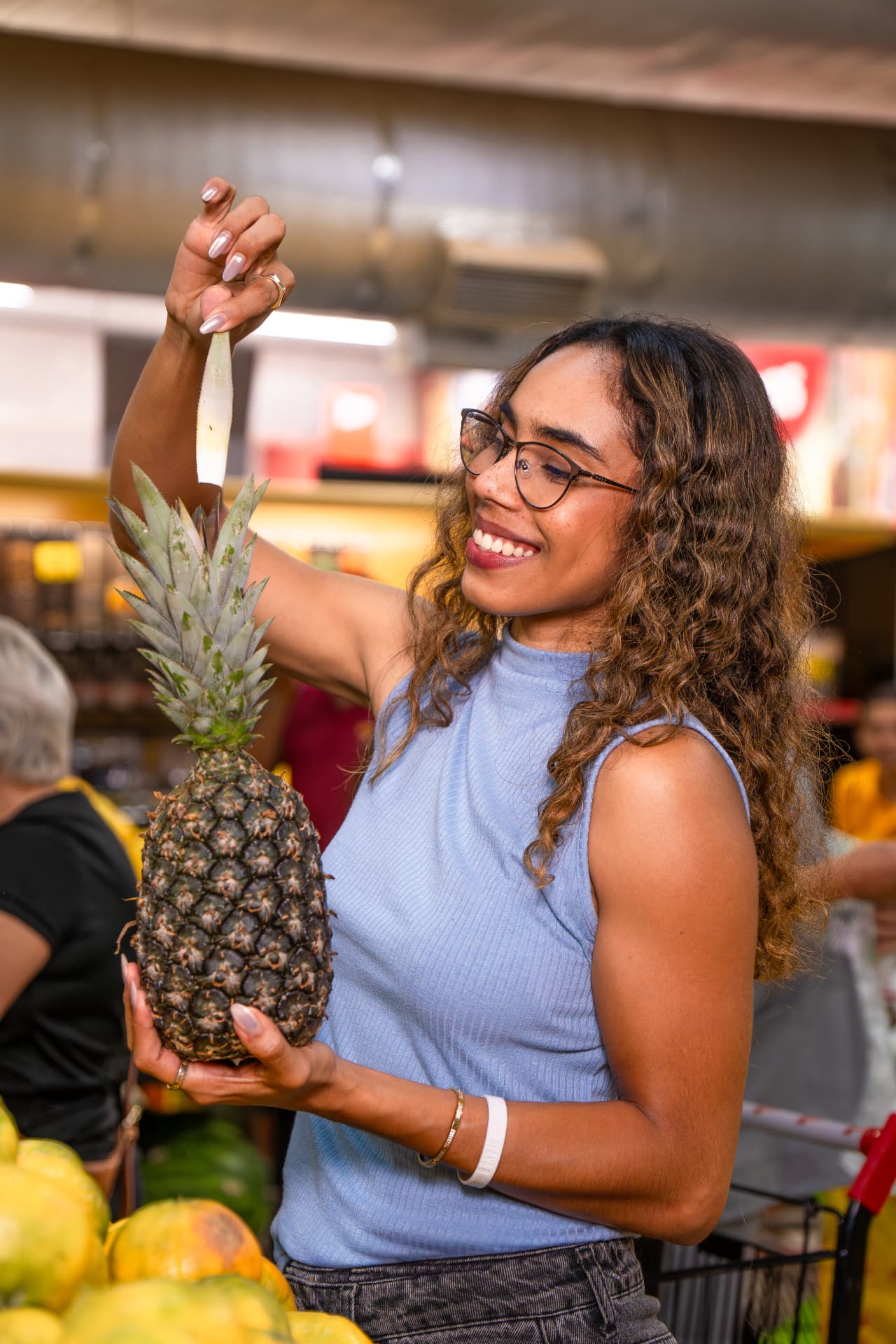 Cliente escolhendo um abacaxi na área de frutas do mercado Hipersenna