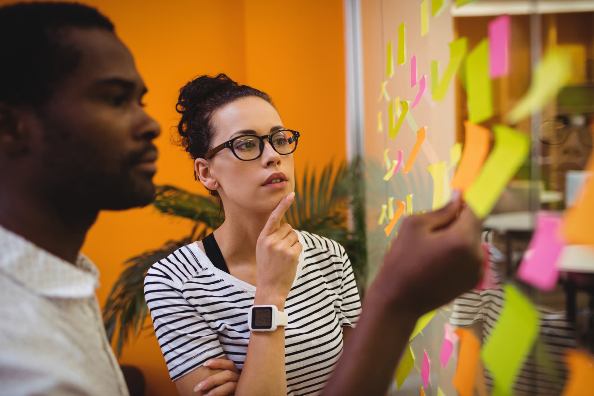 Profissionais analisando ideias em post-its durante reunião de estratégia