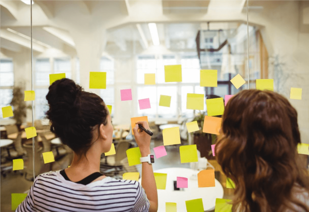 Duas mulheres reunidas fazendo Brainsorming com a ajuda de post-it's