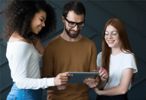 Homem e duas mulheres sorrindo enquanto analisam dados