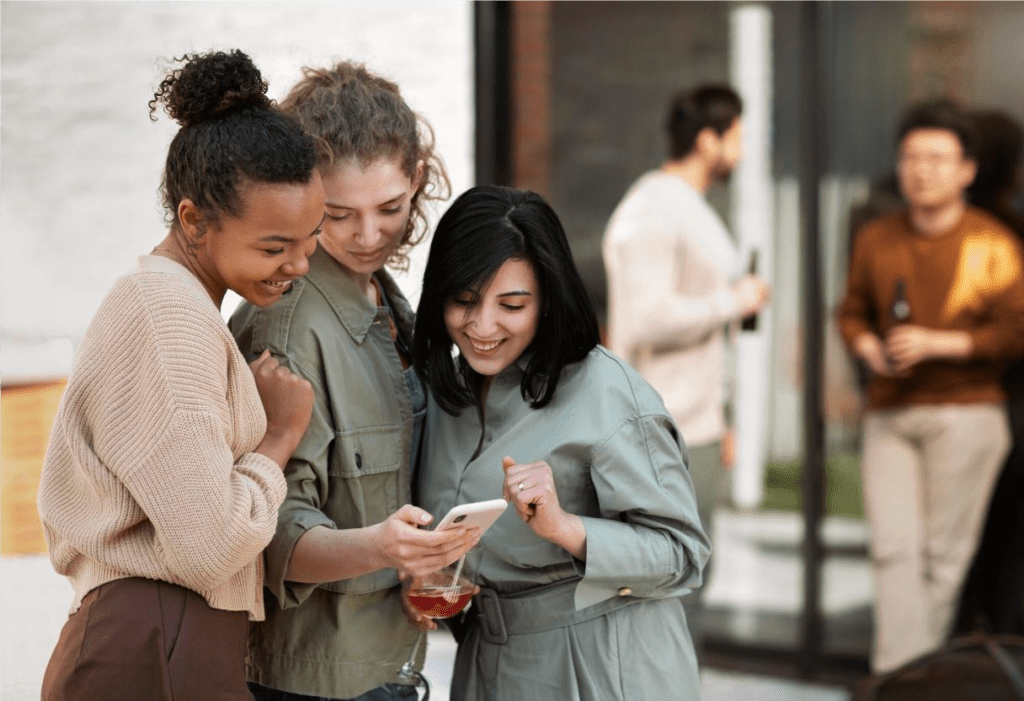 Três mulheres assistindo uma campanha através de um celular