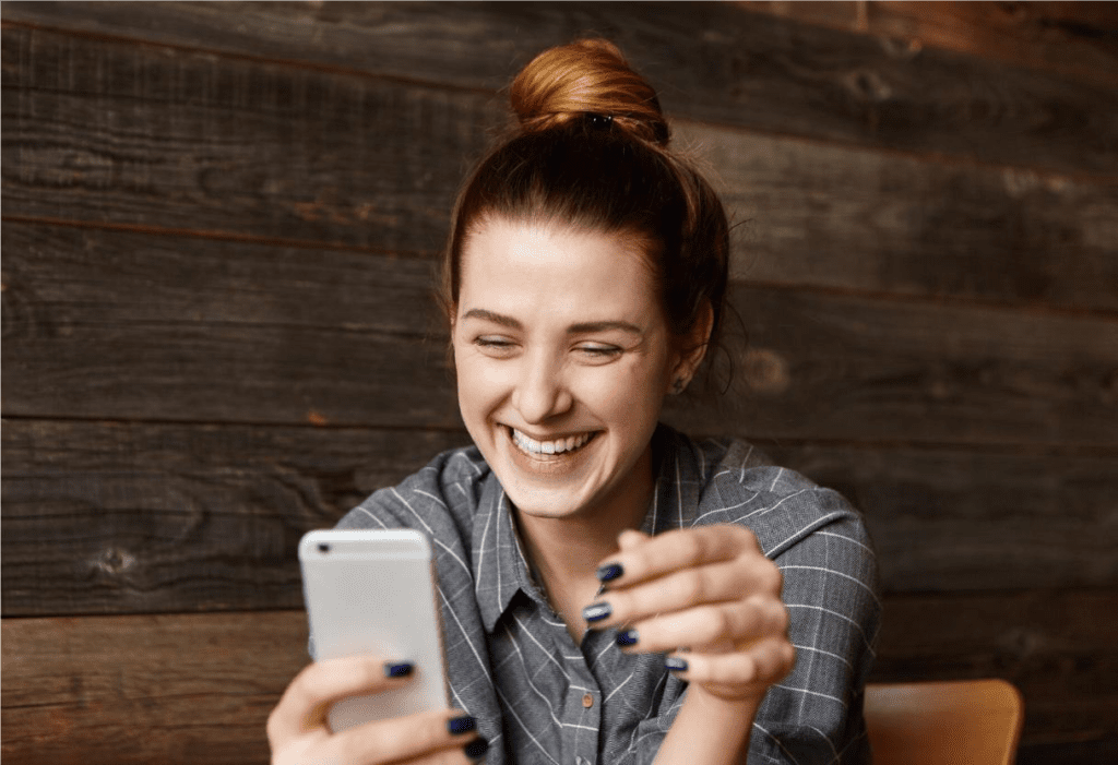 Garota sorrindo para o celular por causa de campanha com referencias a cultura pop