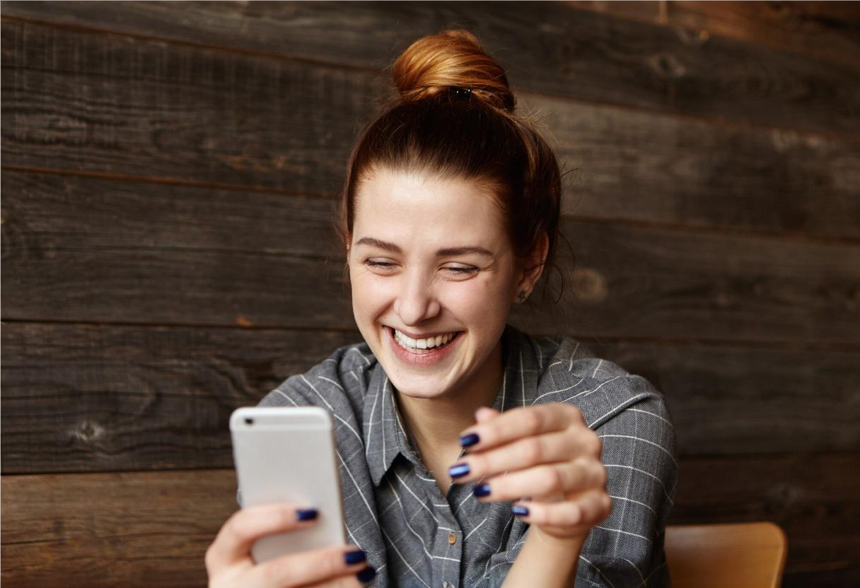 Garota sorrindo para o celular por causa de campanha com referencias a cultura pop