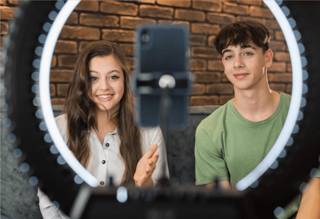 Garoto e garota em frente a equipamento de filmagem, gravando para marketing de influência