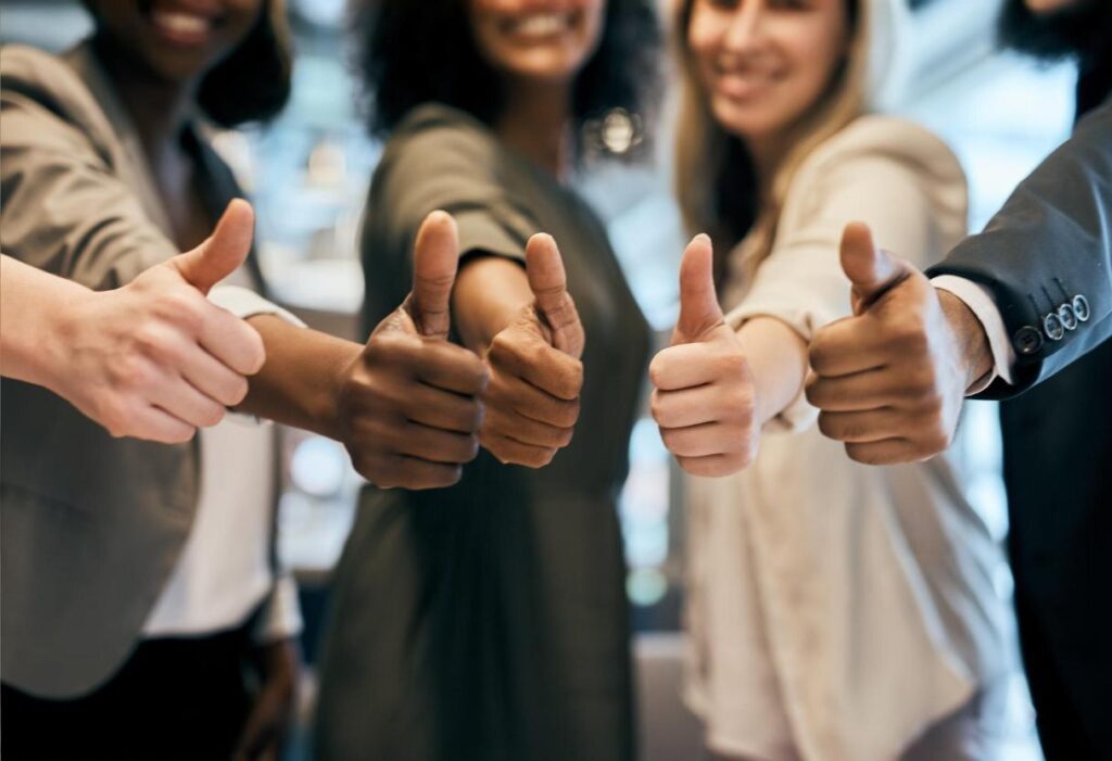 Leads que se transforam em clientes, reunidos e fazendo sinal de joia com as mãos